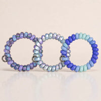 Three blue and lavender Jelly Spiral Hair Ties featuring striped, gradient and mixed colour coil designs.