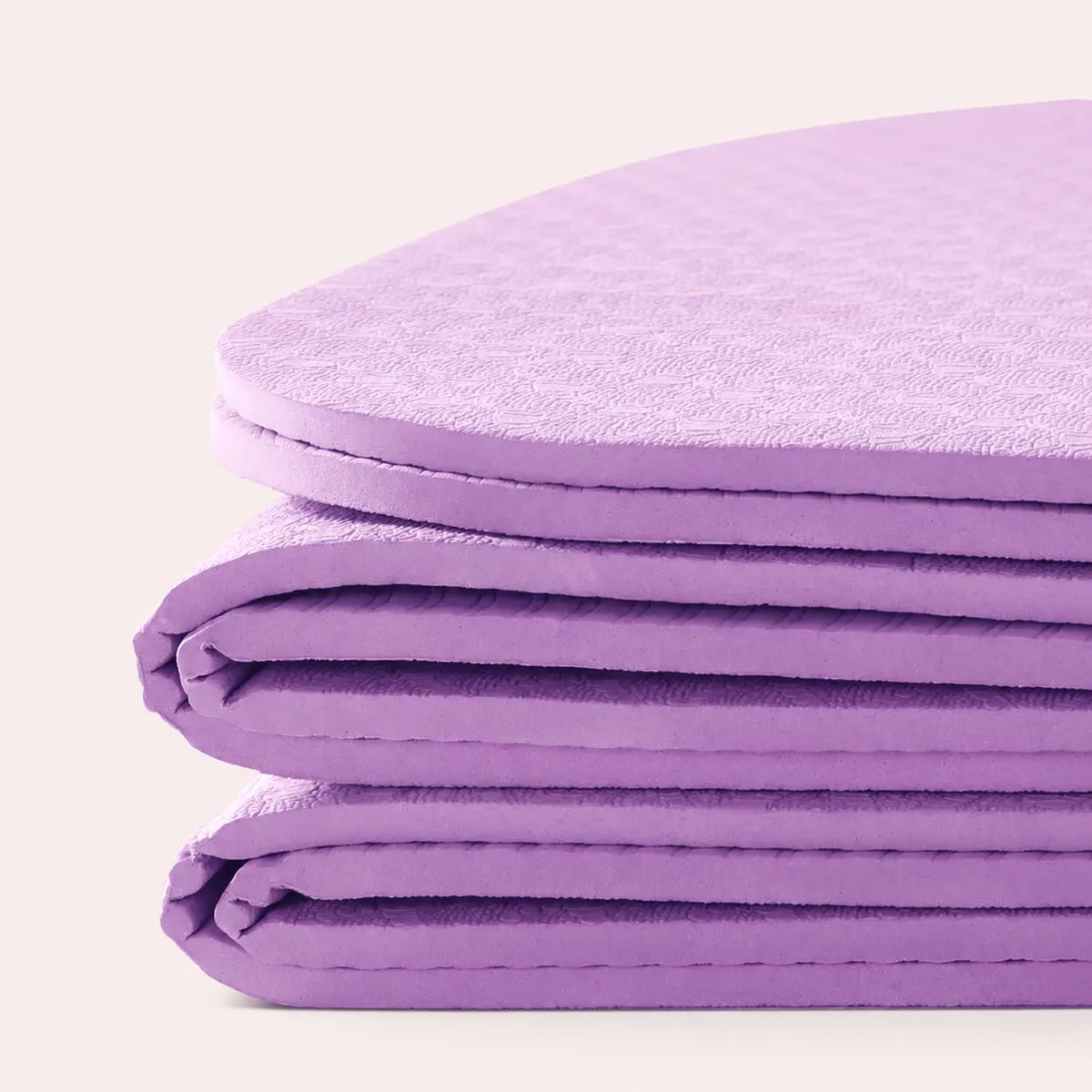 Purple yoga mat folded into a compact stack for travel and home storage