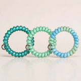 Set of 3 green and teal TPU spiral hair ties with a smooth glossy finish for ponytails and everyday styling.