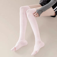 Woman wearing pink over-the-knee compression socks, showcasing slim fit and ergonomic foot support design