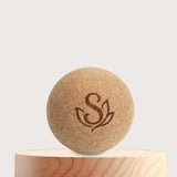 Single cork massage ball displayed on a wooden pedestal. Made from sustainable cork, ideal for relieving tension, supporting trigger point therapy, and myofascial release.