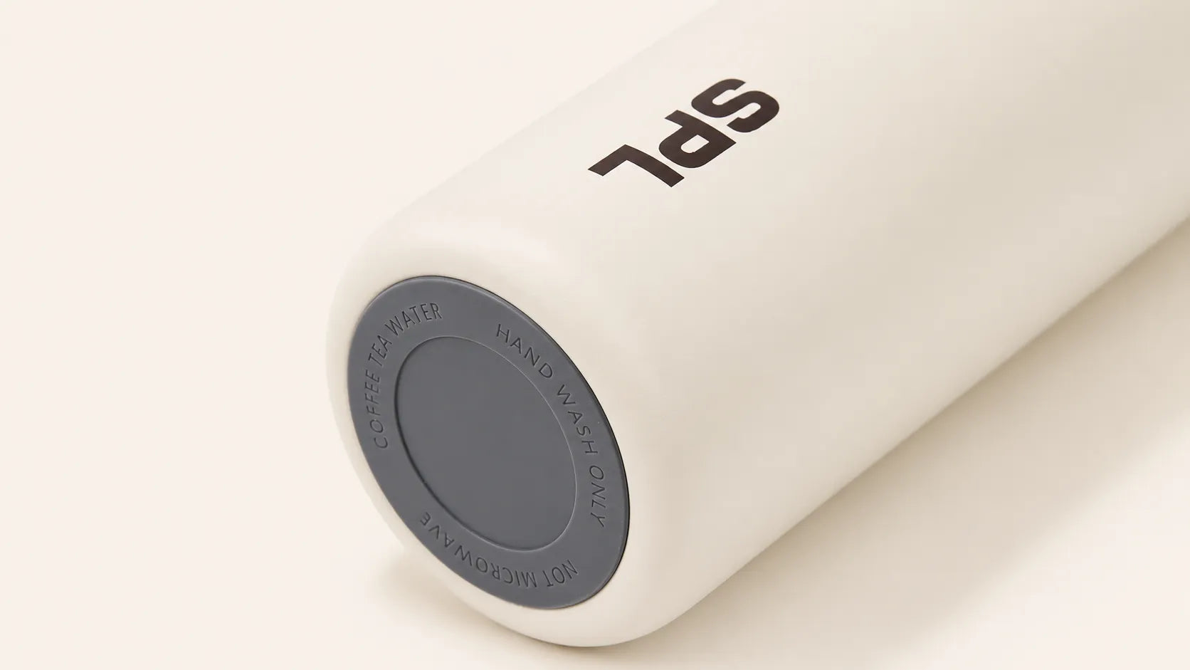 Detail view of the warm white SPL Stainless Steel Straw Bottle with charcoal non-slip base and SPL logo