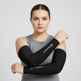 Woman wearing black cooling arm sleeves, arms crossed; breathable compression UV sun protection for running and training.