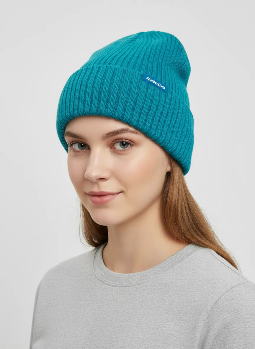 Close angled view of woman in teal blue high rib-knit cuffed beanie (toque) by Sportive Lives; stretchy acrylic knit, one size 56–58 cm.