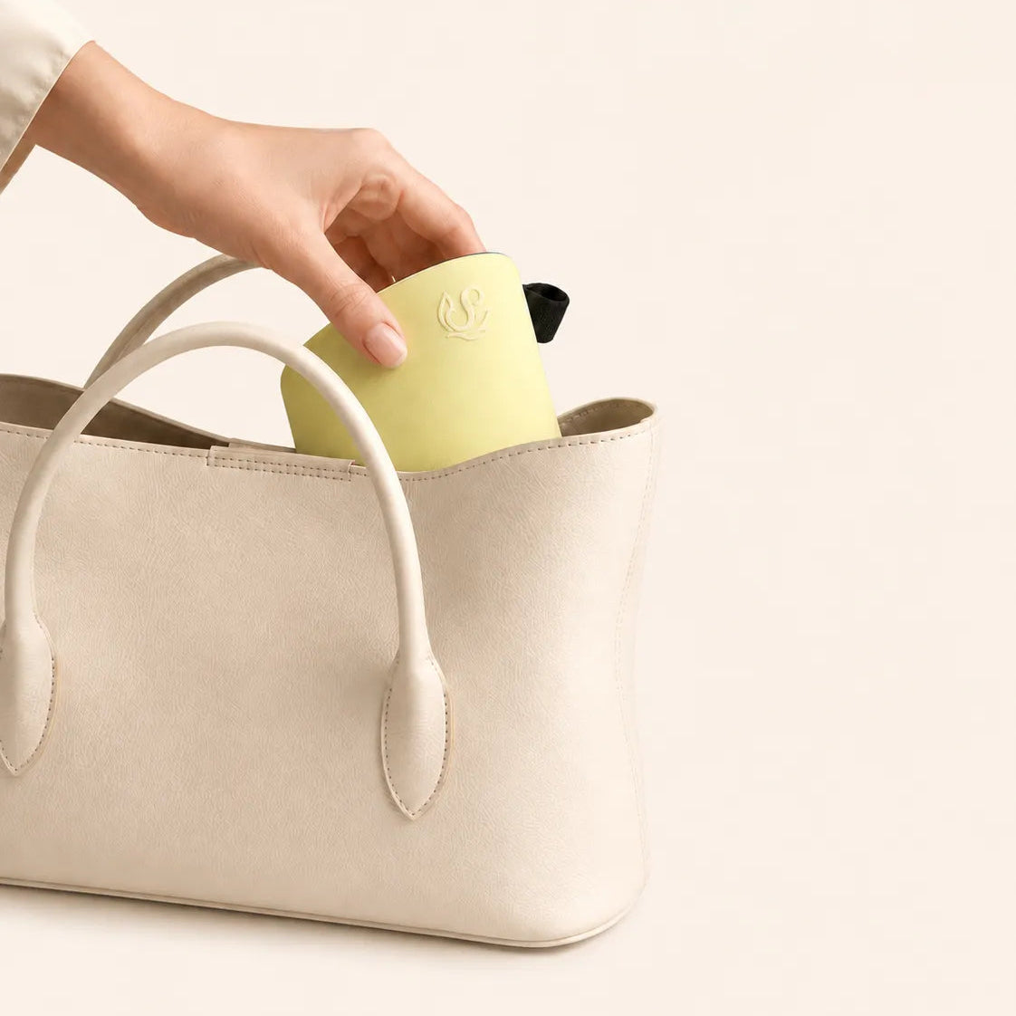 Hand placing a lime Sportive Lives reversible sun visor into a cream handbag for easy travel and storage