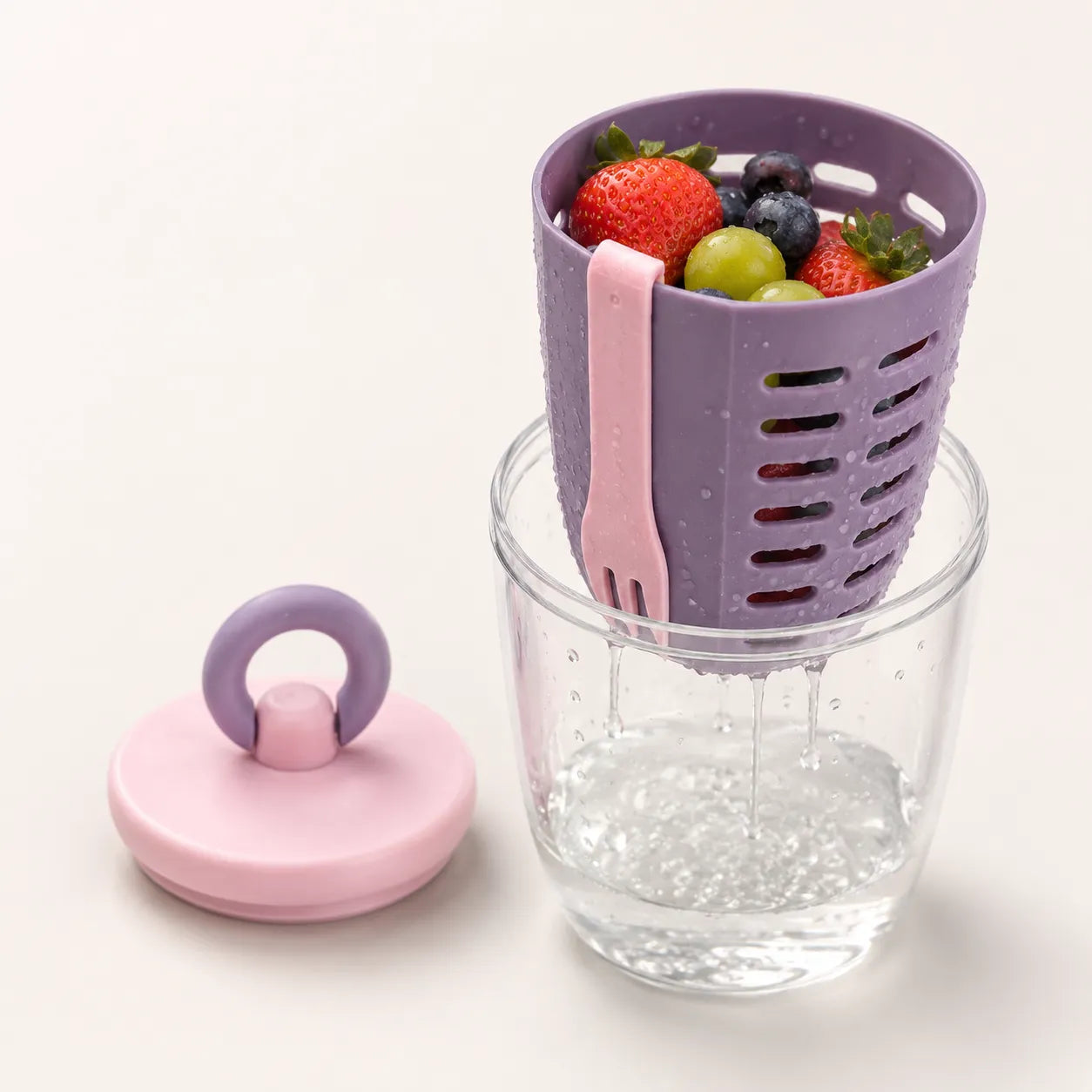 Close-up of the Sportive Lives Portable Salad Cup draining basket rinsing berries and grapes into the clear outer cup