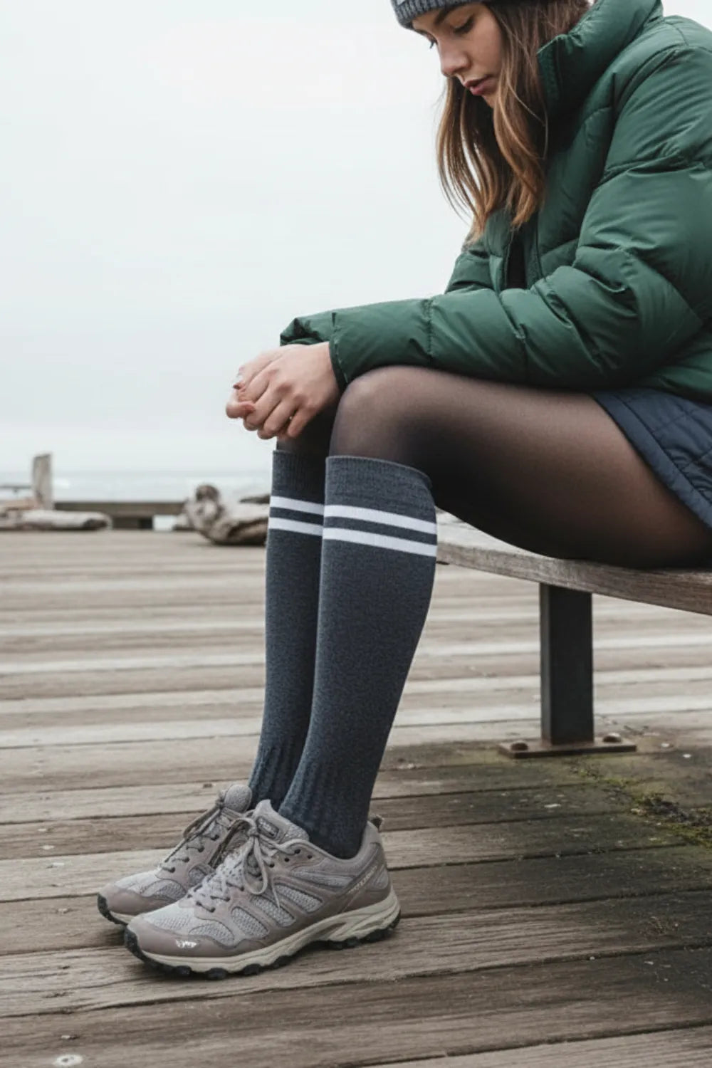 Charcoal gray striped knee-high socks paired with puffer jacket on a seaside boardwalk in Canada.