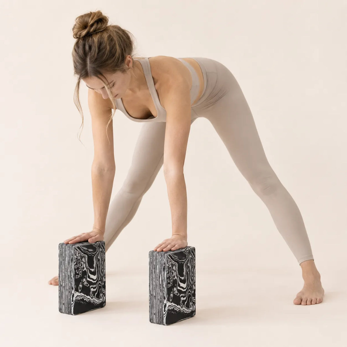 Woman using two EVA yoga blocks for support during a wide-leg forward fold stretch.