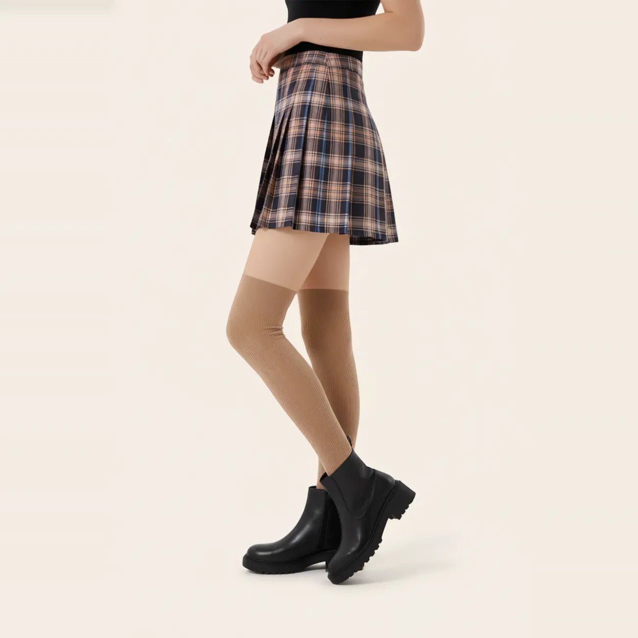 Woman wearing navy blue ribbed over-the-knee socks with a plaid pleated mini skirt and black heels for a classic preppy outfit.