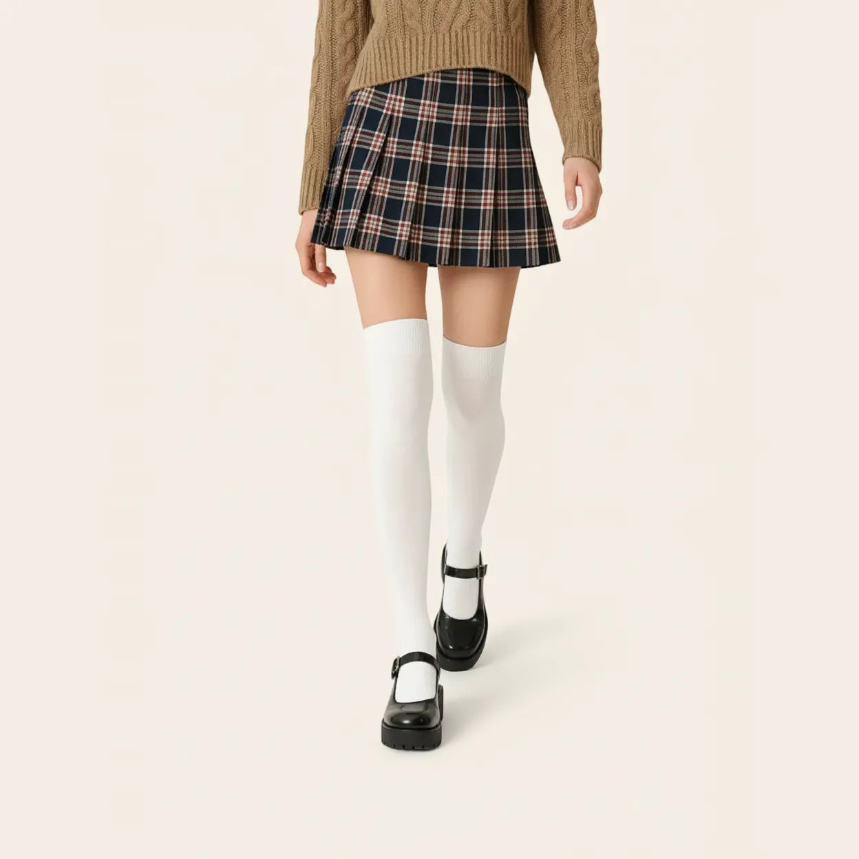 Woman wearing white over-the-knee socks with a plaid mini skirt, brown knit sweater and black Mary Jane shoes for a preppy look.